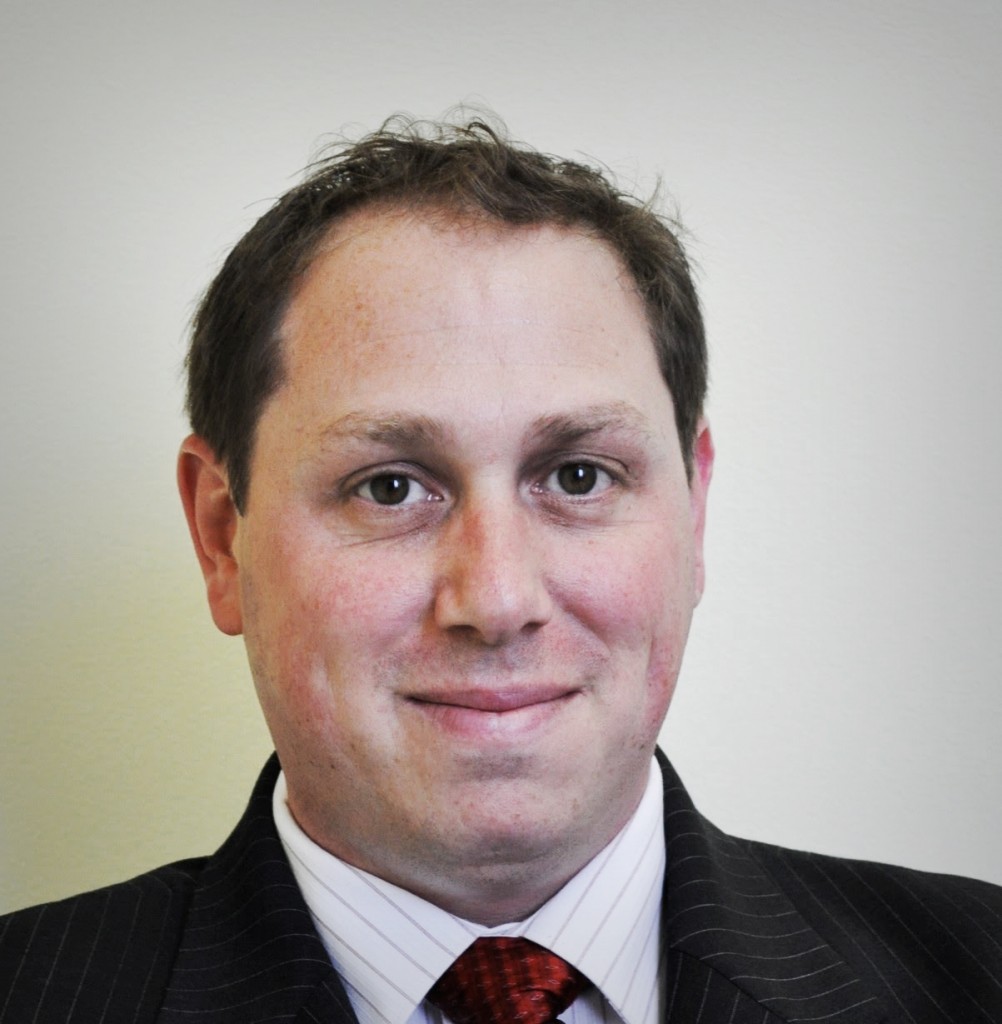 A man in suit and tie smiling for the camera.