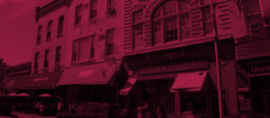 A red lit up building with people walking on the sidewalk.